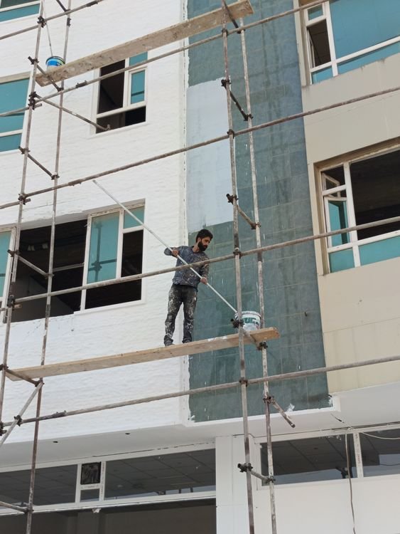 Construction worker on scaffolding painting a building exterior